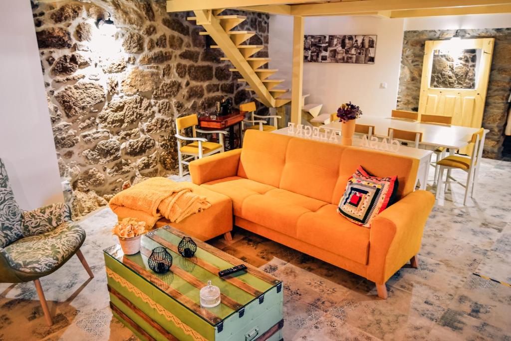 sala de estar con sofá naranja y mesa en A Casa Alegre, en Miranda do Douro