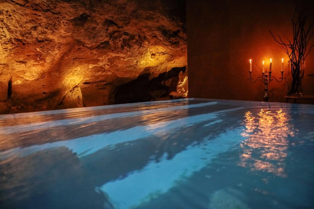 a swimming pool in a cave with two candles at UNAHOTELS One Siracusa in Syracuse