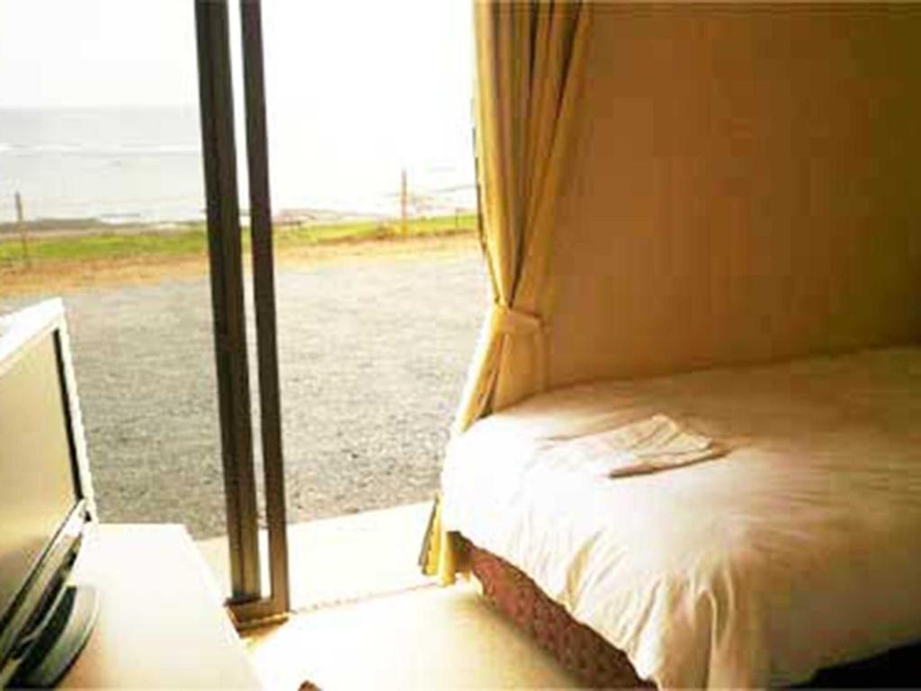 a bedroom with a bed next to a window at Yugaku Resort Kimukura - Vacation STAY 93867v in Tokunoshima