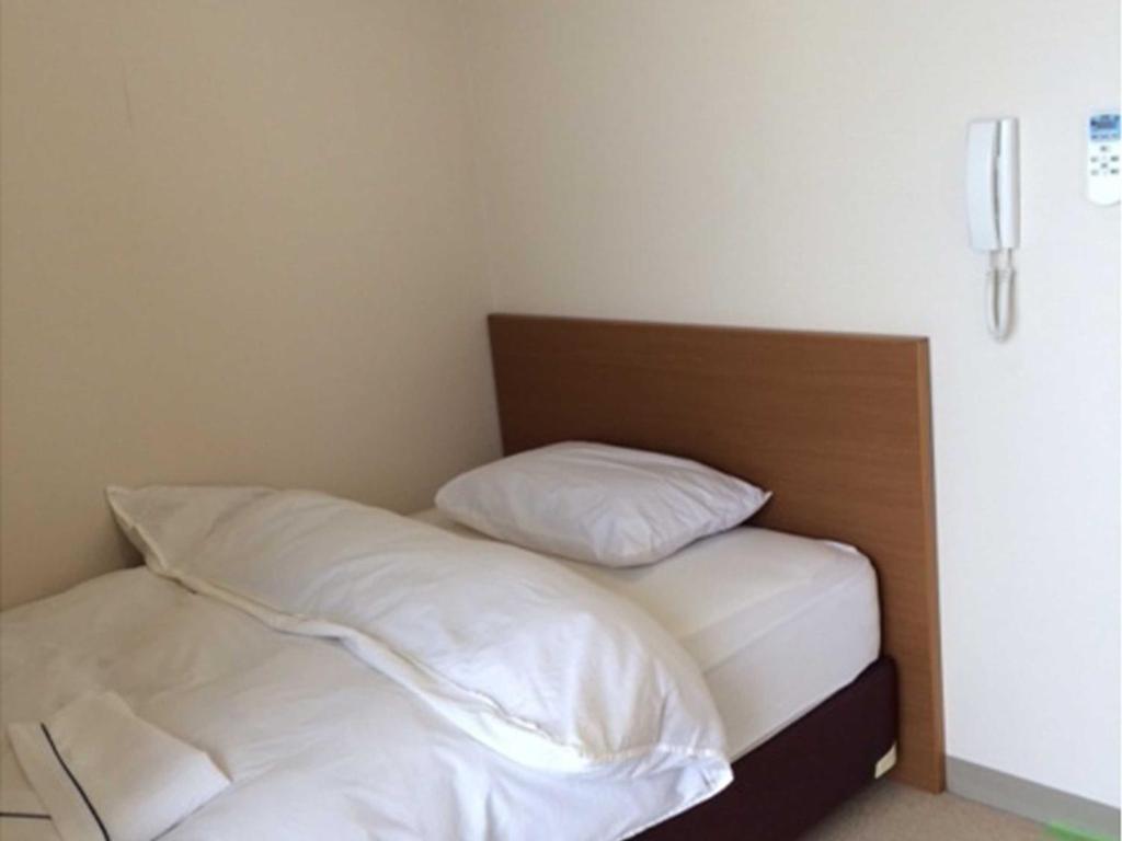Bett mit weißer Bettwäsche und Kissen in einem Zimmer in der Unterkunft Yugaku Resort Kimukura - Vacation STAY 89356v in Tokunoshima
