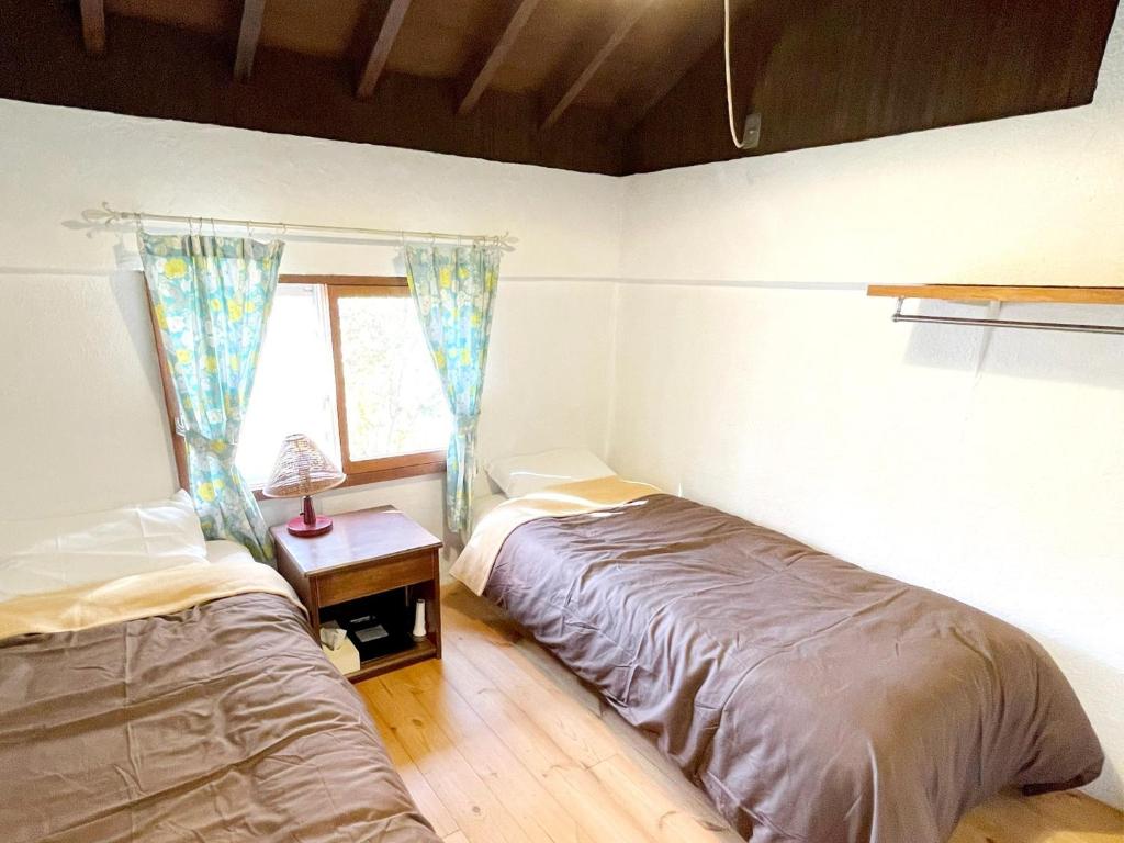 een slaapkamer met 2 bedden, een tafel en een raam bij Gallery HARA & GUESTHOUSE - Vacation STAY 95372v in Hara