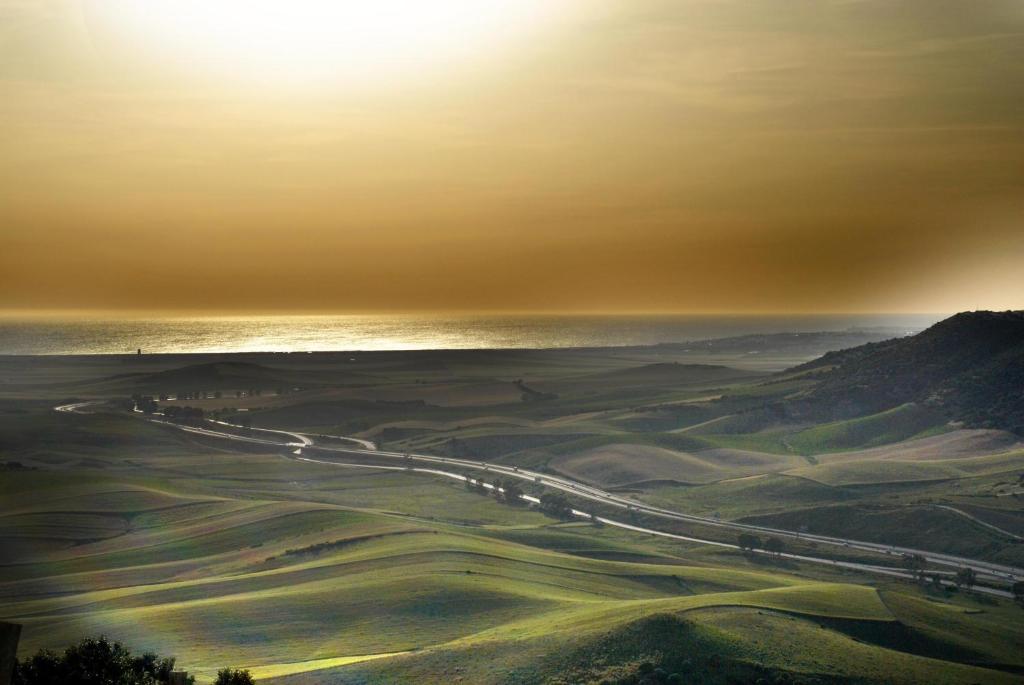 a road in the middle of a field with the sun at Hotel Boutique V in Vejer de la Frontera