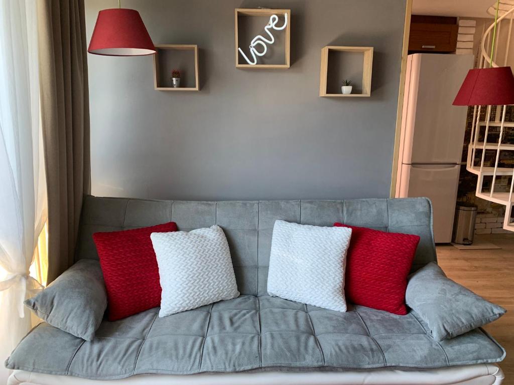 a gray couch with red and white pillows on it at Lovely penthouse with an indoor fireplace in Sofia