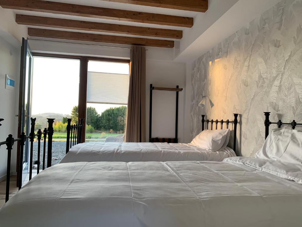 Duas camas num quarto com uma grande janela. em Rectoral de Boente em Arzúa