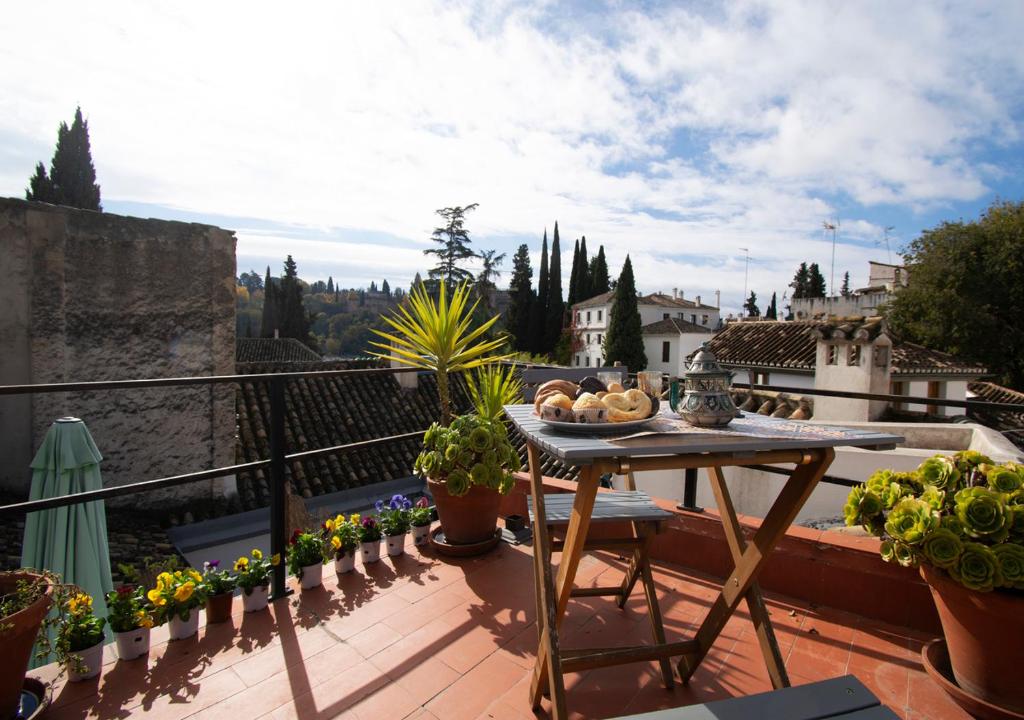 a table on a balcony with flowers and plants at Mirador Alhambra - 2 Private Terraces - Wifi - in Granada