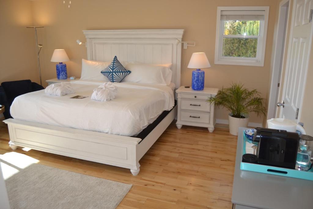 sypialnia z białym łóżkiem z 2 stolikami nocnymi i telewizorem w obiekcie Salish B&B and Spa w mieście West Kelowna