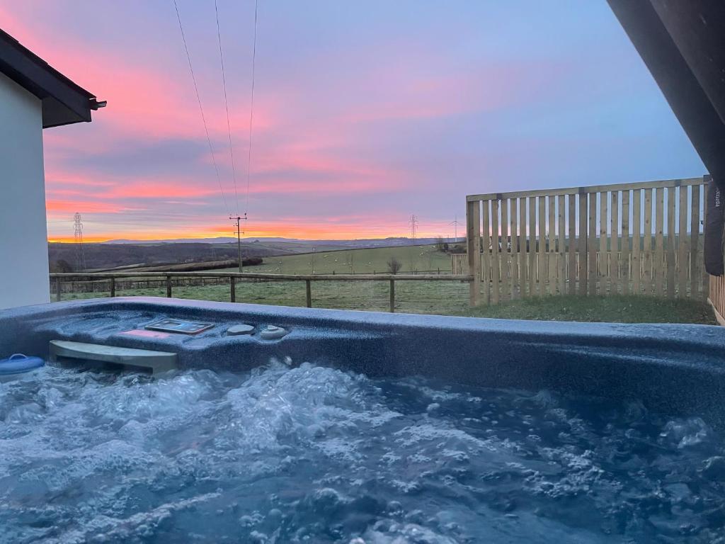 a jacuzzi tub with a sunset in the background at NEW! Country boutique escape . HOT TUB in Weare Giffard