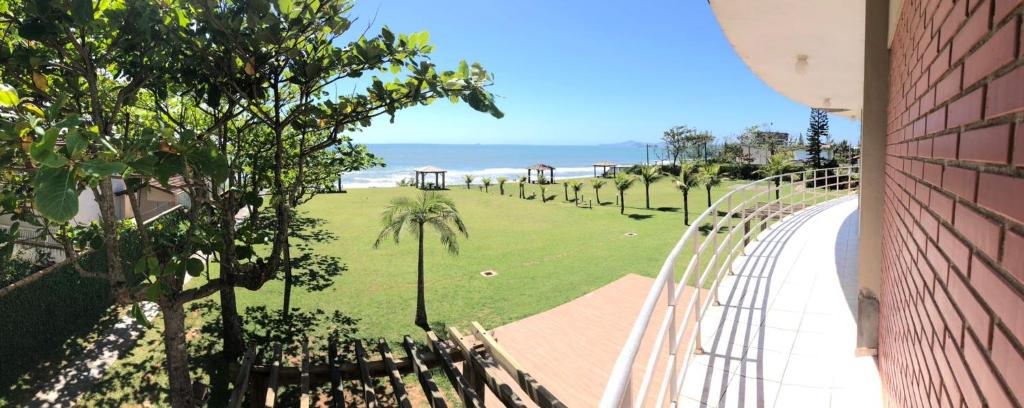 uma vista para um parque com palmeiras e o oceano em Flamboyant Hotel em Barra Velha
