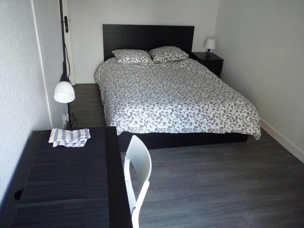 Un dormitorio con una cama y una mesa con una silla. en Résidence Kerhallet, en Brest