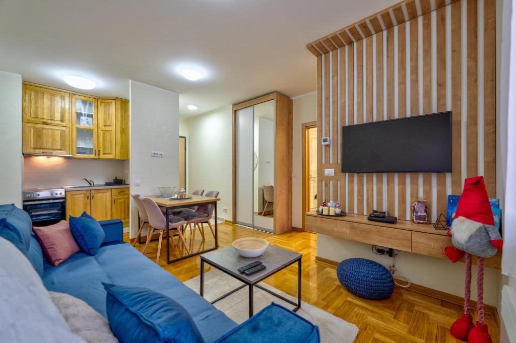 a living room with a blue couch and a kitchen at Apartman Sanjalica in Zlatibor