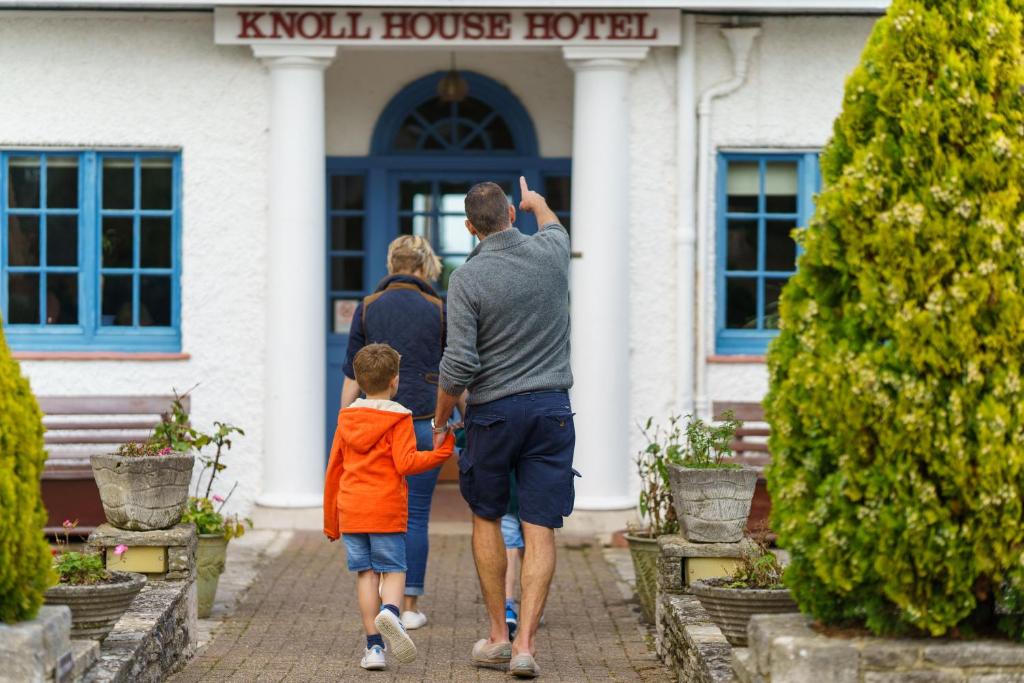 un hombre y un niño entrando en una casa en Knoll House, en Studland