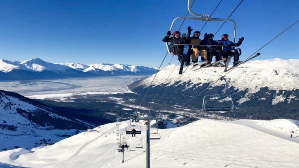 a group of people riding on a ski lift at Chair Four Por Favor - Walk Almost Anywhere at Alyeska Resort! in Girdwood