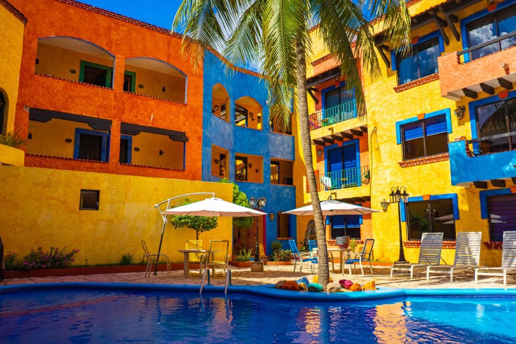 a beach with a pool and a large building at Hacienda Maria Bonita Hotel in Playa del Carmen