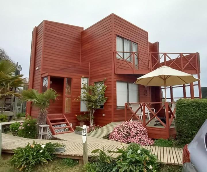una casa roja con un paraguas delante en Condominio Don Alberto, en Pichilemu