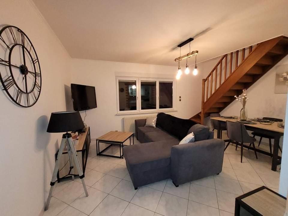 a living room with a couch and a clock on the wall at Appartement cosy style industriel in Bourges