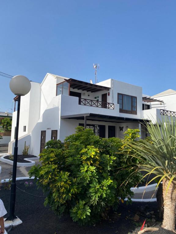 ein weißes Haus mit vielen Pflanzen davor in der Unterkunft Casa Norah Pc in Puerto del Carmen