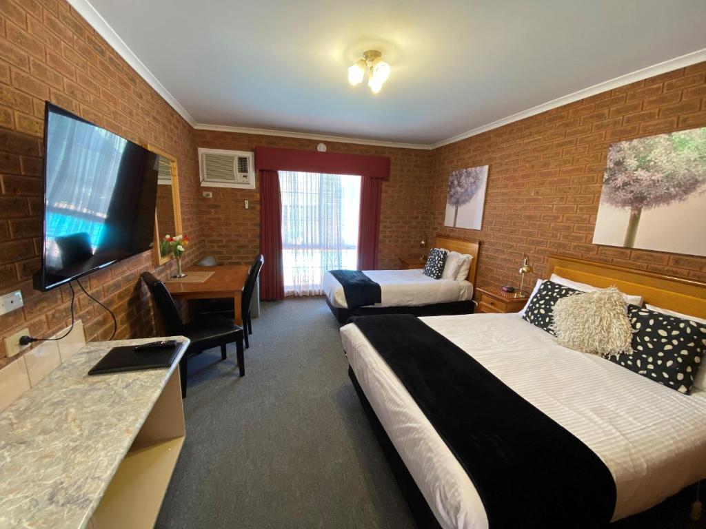 Habitación de hotel con 2 camas y TV de pantalla plana. en Central Yarrawonga Motor Inn en Yarrawonga