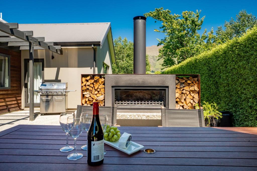 a table with a bottle of wine and wine glasses at Modern Lake Haven - Wanaka Holiday Home in Wanaka