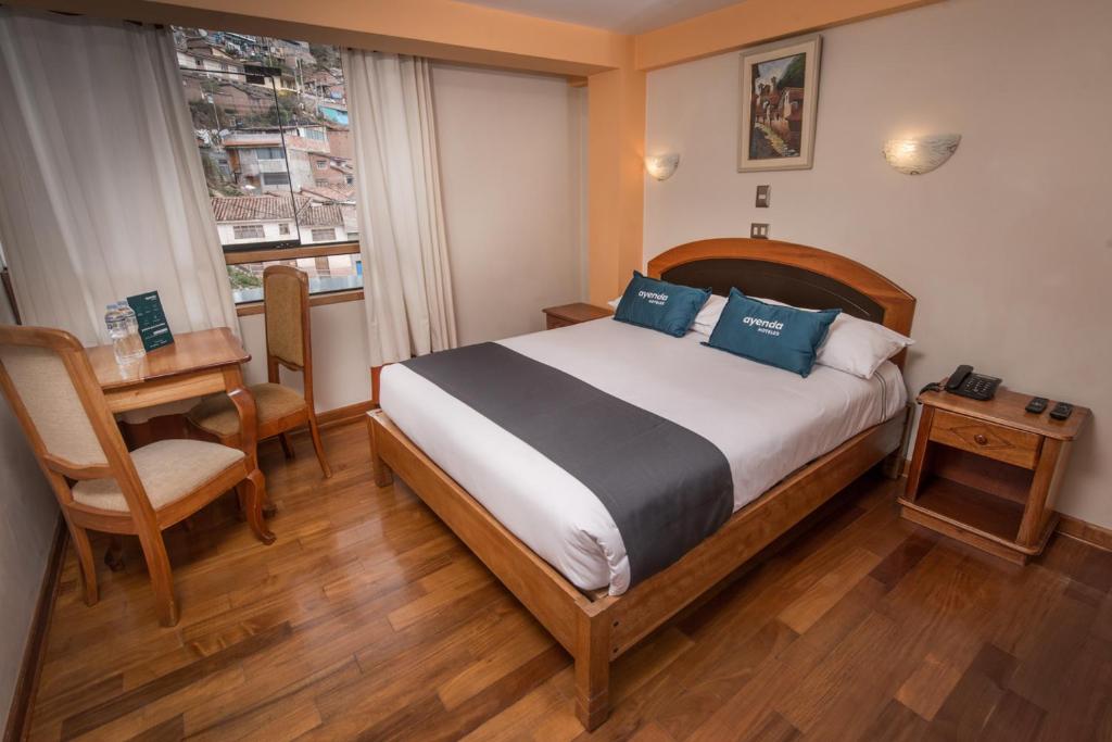1 dormitorio con cama, mesa y ventana en Cascada del Inka, en Cusco