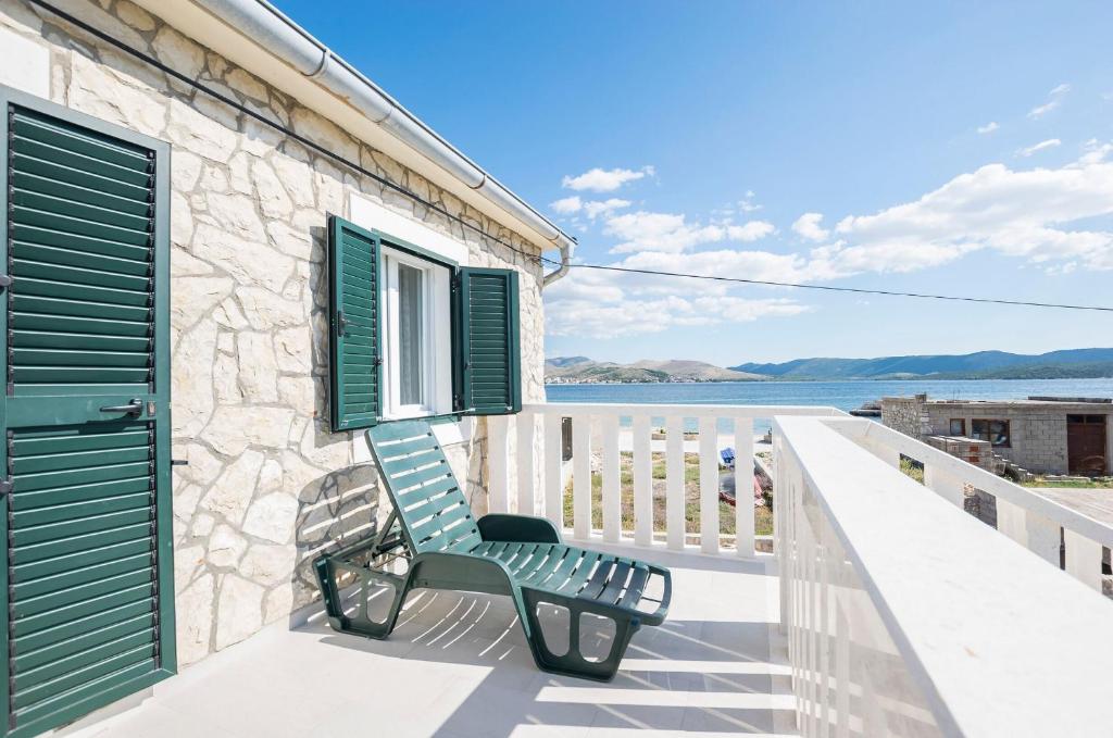 a green bench sitting on the balcony of a house at Apartment Island Sun Terrace in Krapanj