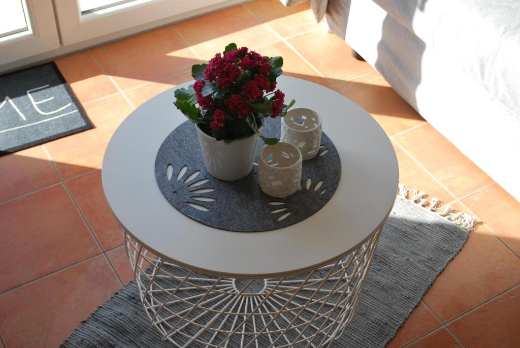 Una mesa blanca con un jarrón de flores. en Ferienwohnung K38 "Sonnenblume", en Graal-Müritz