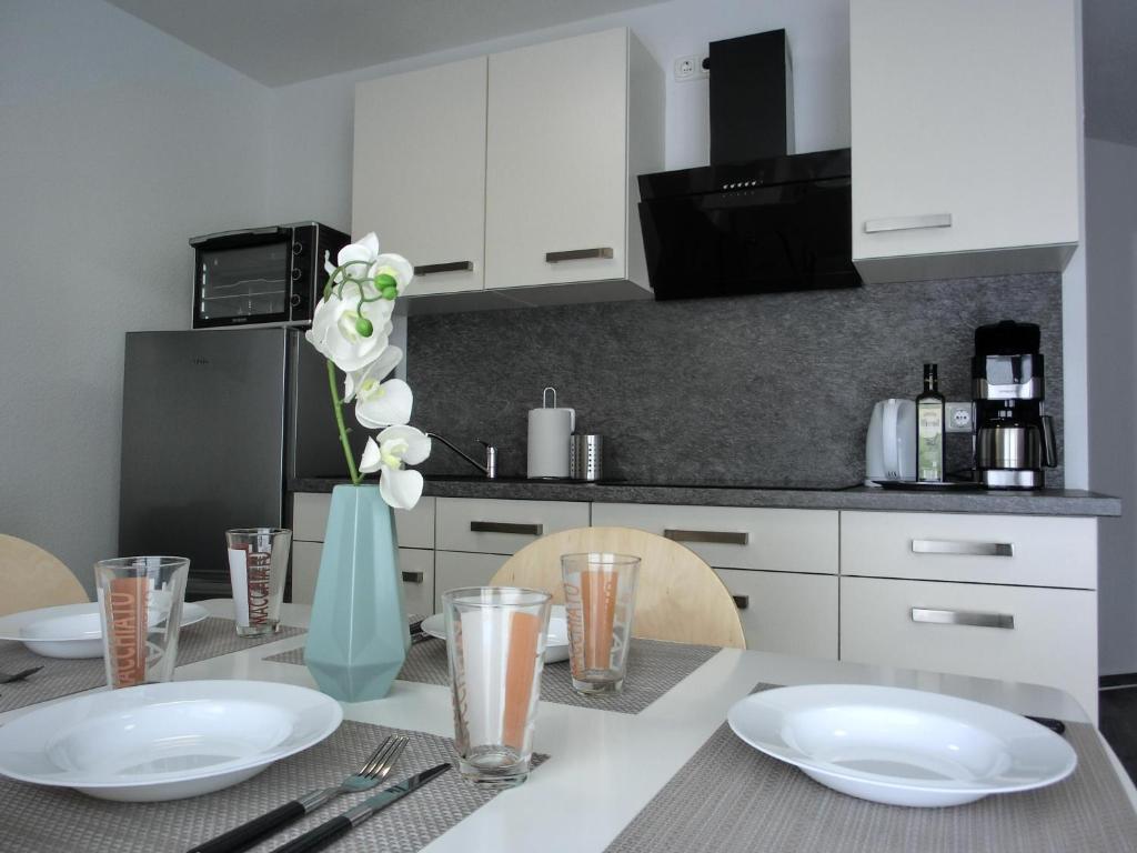 una cocina con una mesa con platos y utensilios blancos en Ferienwohnung KWi 84 EG en Graal-Müritz