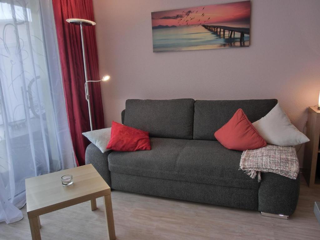 uma sala de estar com um sofá cinzento com almofadas vermelhas em Ferienwohnung KWV 7 EG em Graal-Müritz