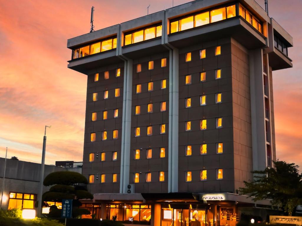 budynek z wieloma oknami o zachodzie słońca w obiekcie Hachinohe Plaza Hotel w mieście Hachinohe