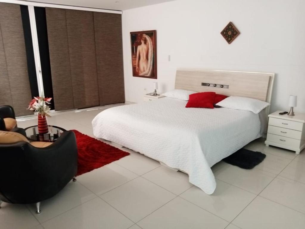 a white bedroom with a large bed and a chair at Casa Boutique HNP in Barrancabermeja