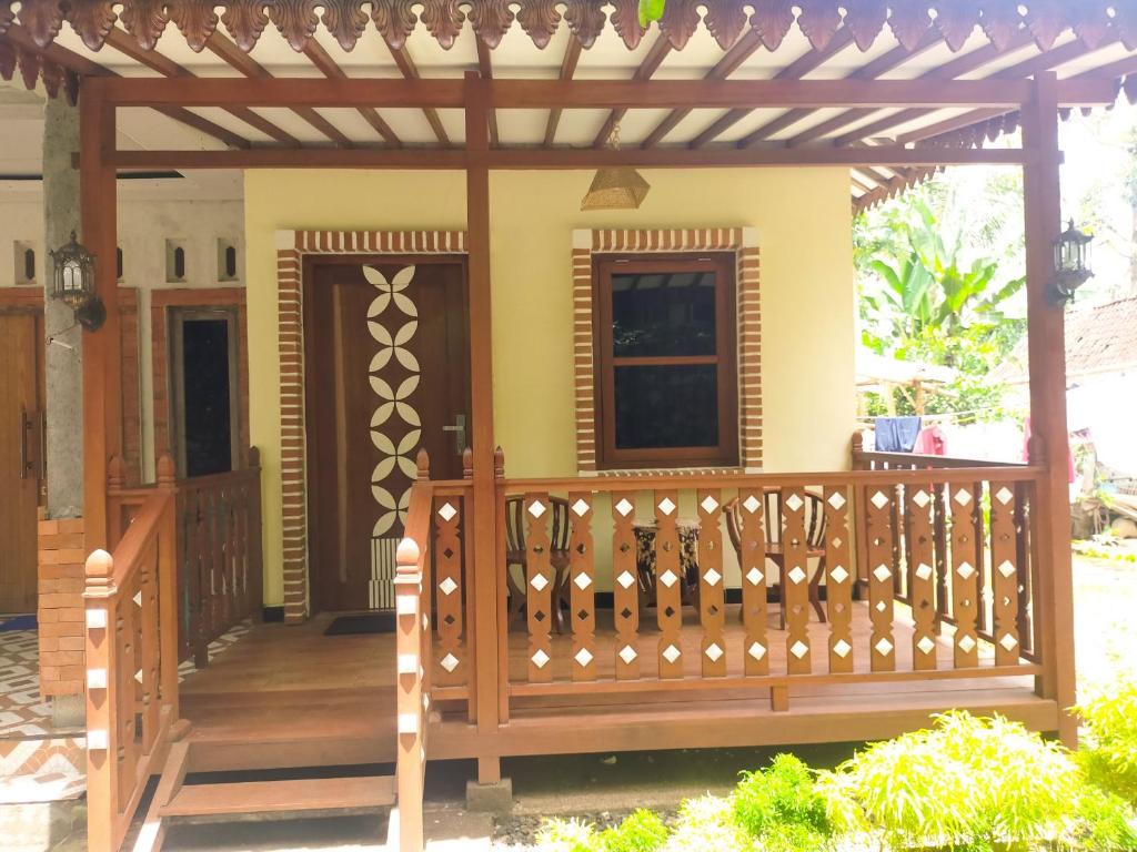 eine Holzterrasse mit einer Pergola auf einem Haus in der Unterkunft Anang Bed & Breakfast Syariah by Ndalem Beong in Magelang