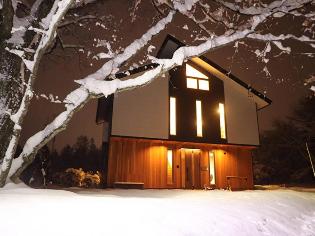 a cabin lit up in the snow at night at Hakuba Hokujo in Hakuba