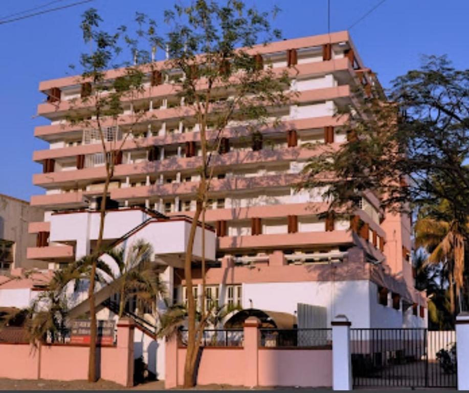 a tall pink building with trees in front of it at Vitthal Inn in Pandharpur