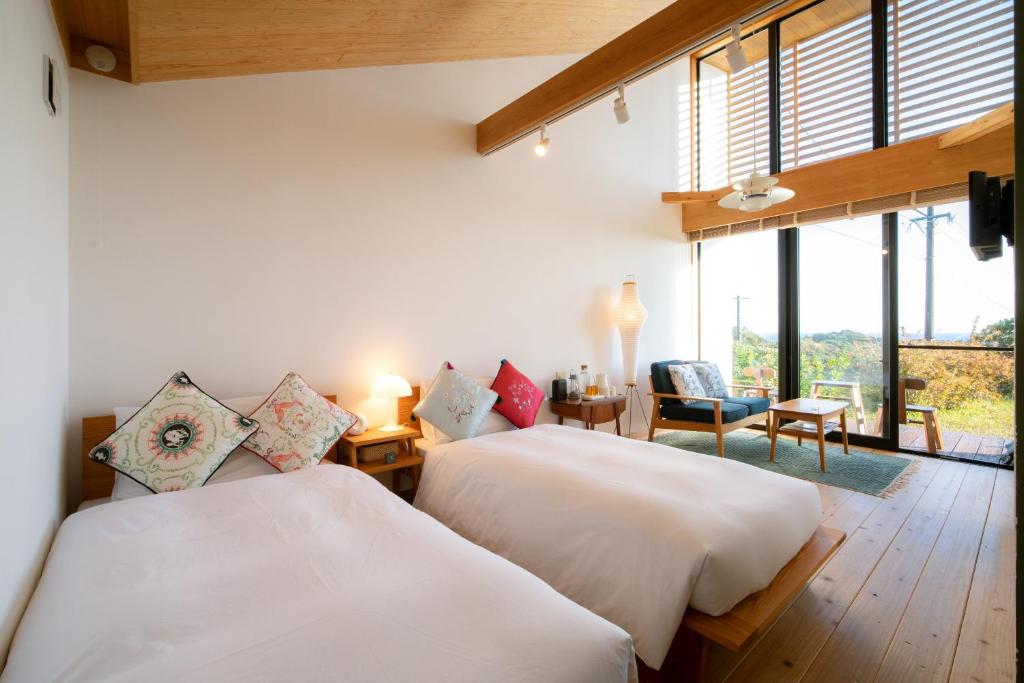 two beds in a room with a large window at Ananda Chillage Yakushima in Yakushima