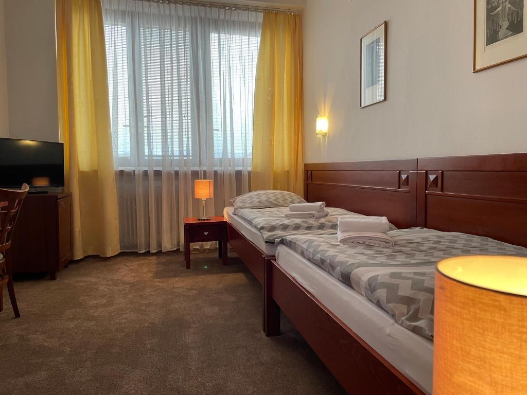 a hotel room with two beds and a television at Hotel Bothe in Považská Bystrica