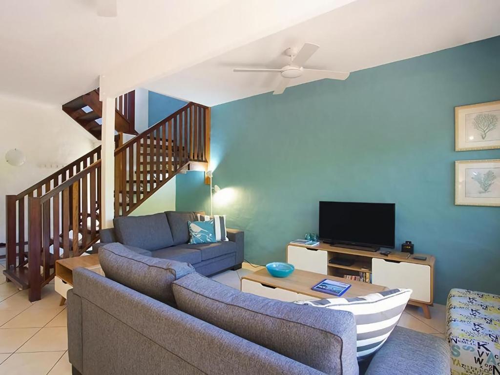 ein Wohnzimmer mit einem Sofa und einem TV in der Unterkunft Little Cove Townhouse 5 Pandanus Street 14 in Noosa Heads