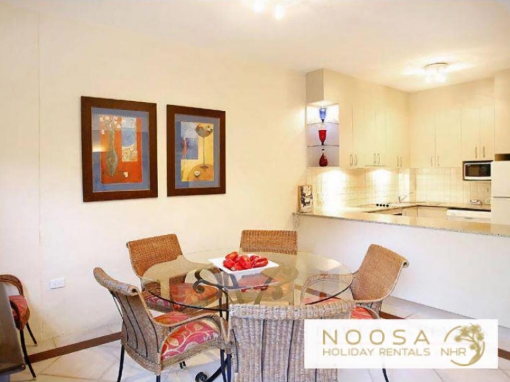 a kitchen and dining room with a glass table and chairs at Little Cove Townhouse 3 Pandanus Street 14 in Noosa Heads
