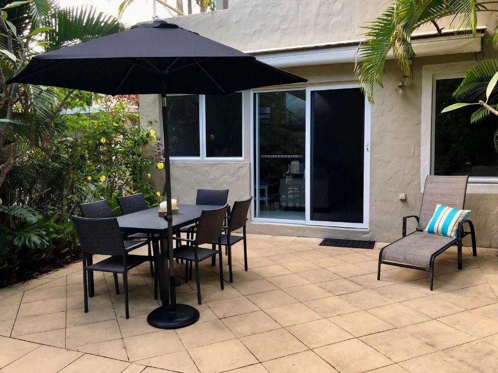 a table with chairs and an umbrella on a patio at Little Cove Townhouse 9 Pandanus Street 14 in Noosa Heads