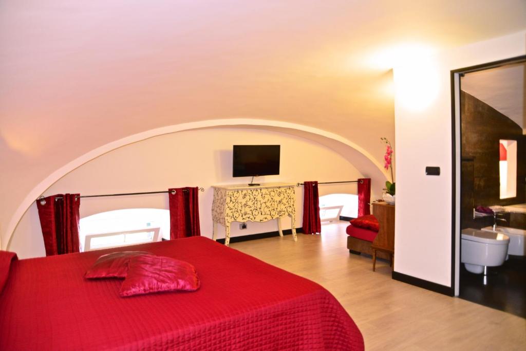 a bedroom with a red bed with a tv on the wall at B&B Torre Porta Marina in Ventimiglia