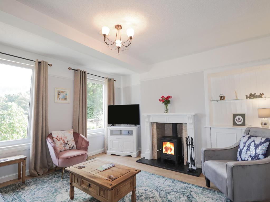 a living room with a fireplace and a tv at 2 Riverside in Inverness
