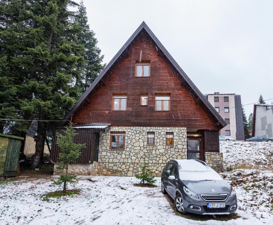a car parked in front of a house in the snow at APARTMANI Arsic in Jahorina