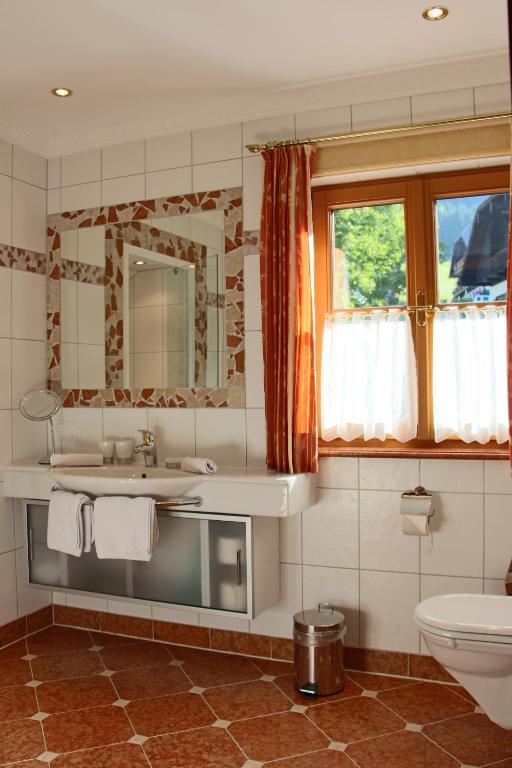 un bagno con lavandino, water e specchio di Ferienwohnung Schossleitner - der Wohlfühl-Ansitz am Wolfgangsee mit Weitblick a Sankt Gilgen