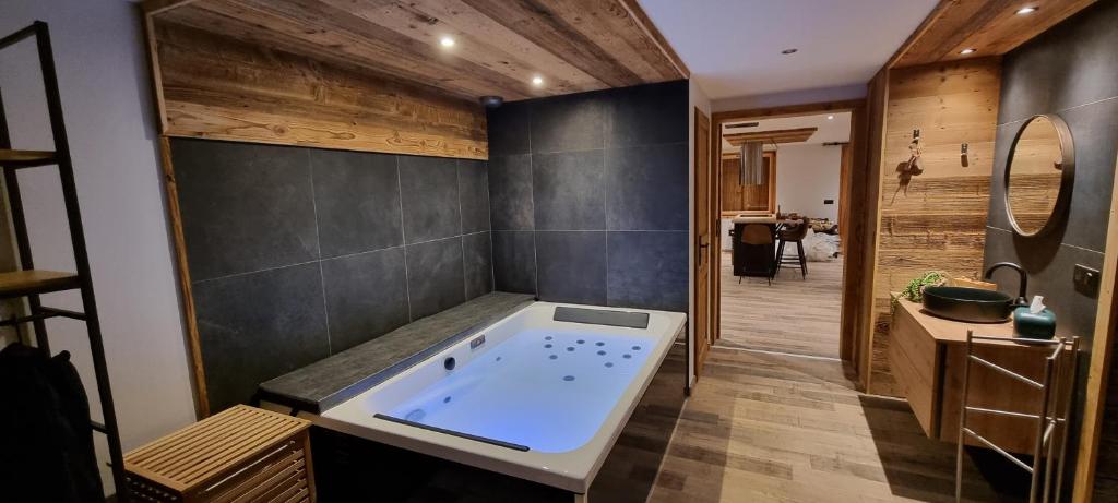 La salle de bains est pourvue d'une grande baignoire et de murs en bois. dans l'établissement L'échappée belle Villaroger, à Villaroger