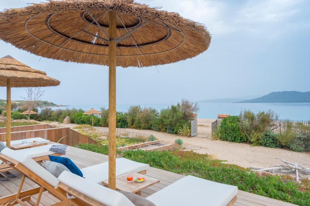 un patio con sombrilla y sillas y vistas al océano en Boutique hôtel Château Rouher, en Propriano