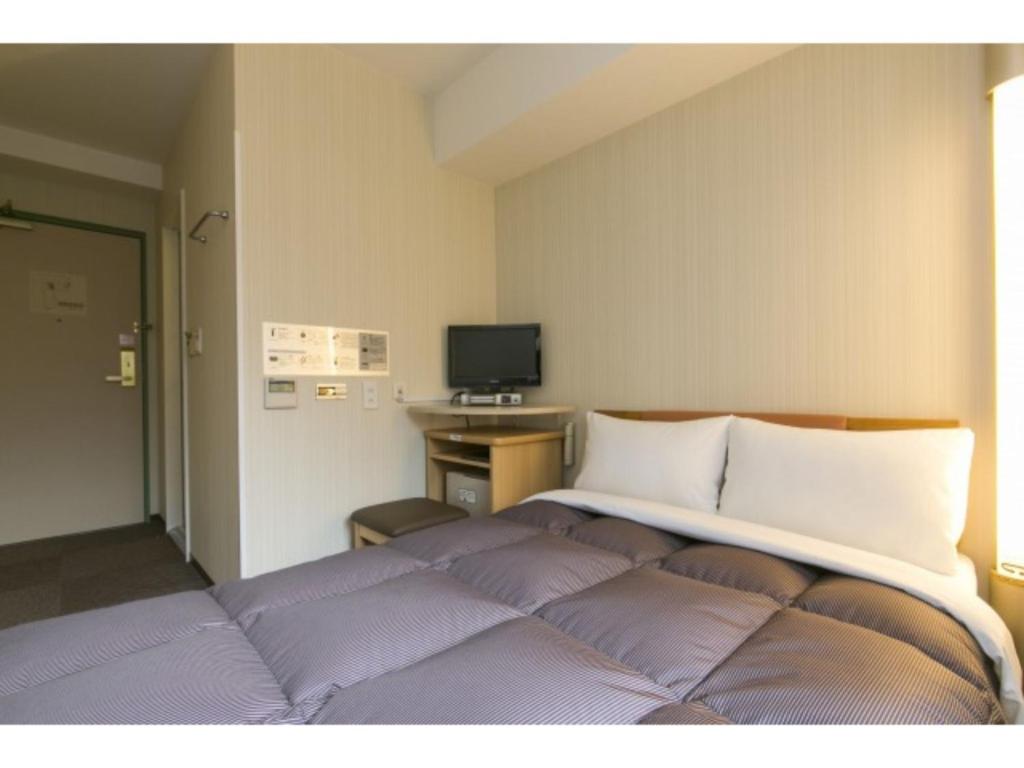 盛岡的住宿－R&B HOTEL MORIOKA EKIMAE - Vacation STAY 38796v，一间卧室配有一张带紫色枕头的大床