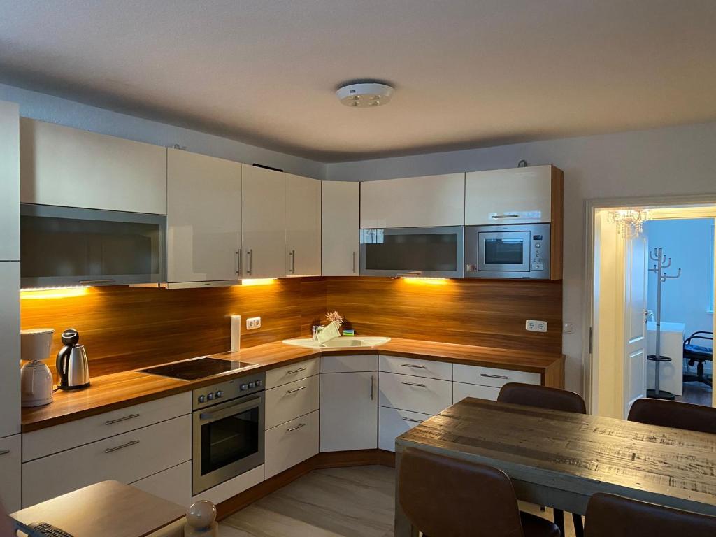 a kitchen with white cabinets and a table and a dining room at Geräumige und schöne Wohnung direkt in der Lübecker Innenstadt in Lübeck