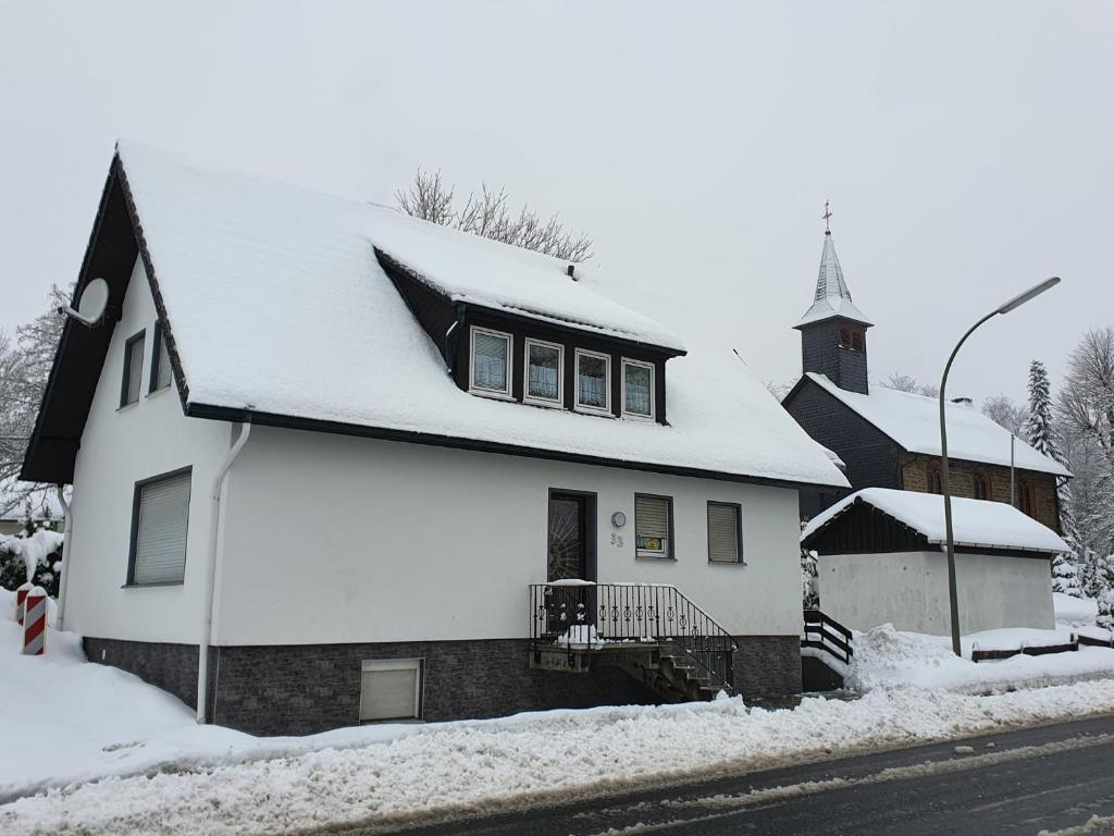 una iglesia blanca con techo cubierto de nieve en Ferienhaus Trudi en Winterberg