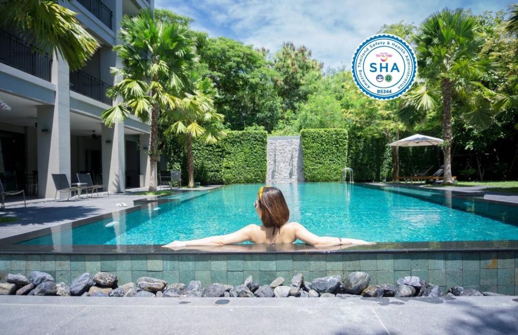una mujer tendida en una piscina en un hotel en The Sala Pattaya - SHA Certified, en Jomtien Beach