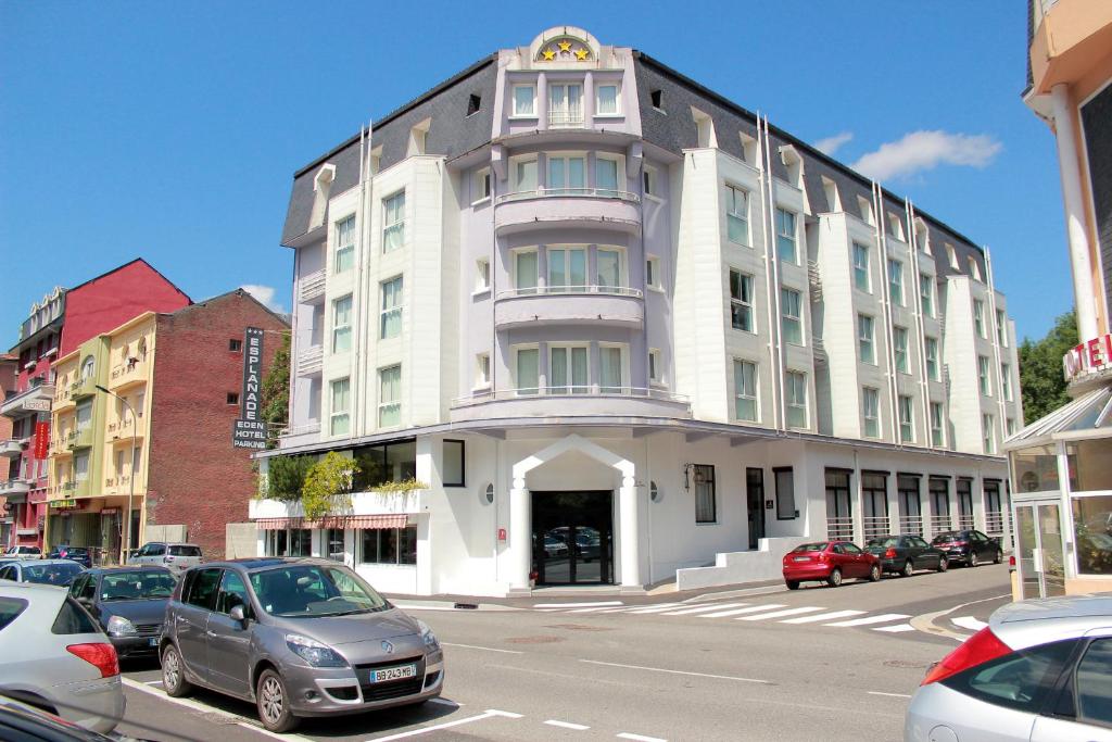 um grande edifício branco com carros estacionados em frente em Hôtel Esplanade Eden em Lourdes