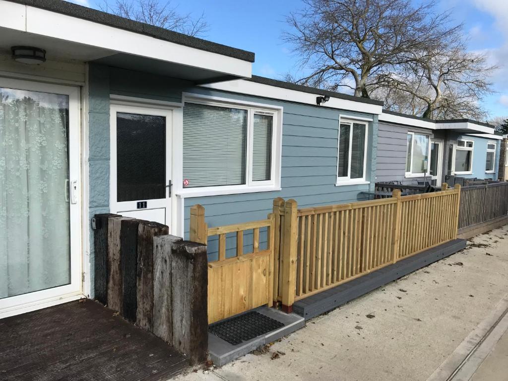 a blue house with a wooden fence at 2 Bedroom Chalet SB11, Sandown Bay, Dog Friendly in Sandown