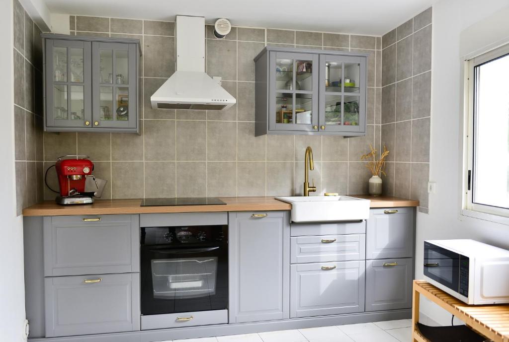 a kitchen with white cabinets and a sink at L’appartement - Jardin Secret in Marseille